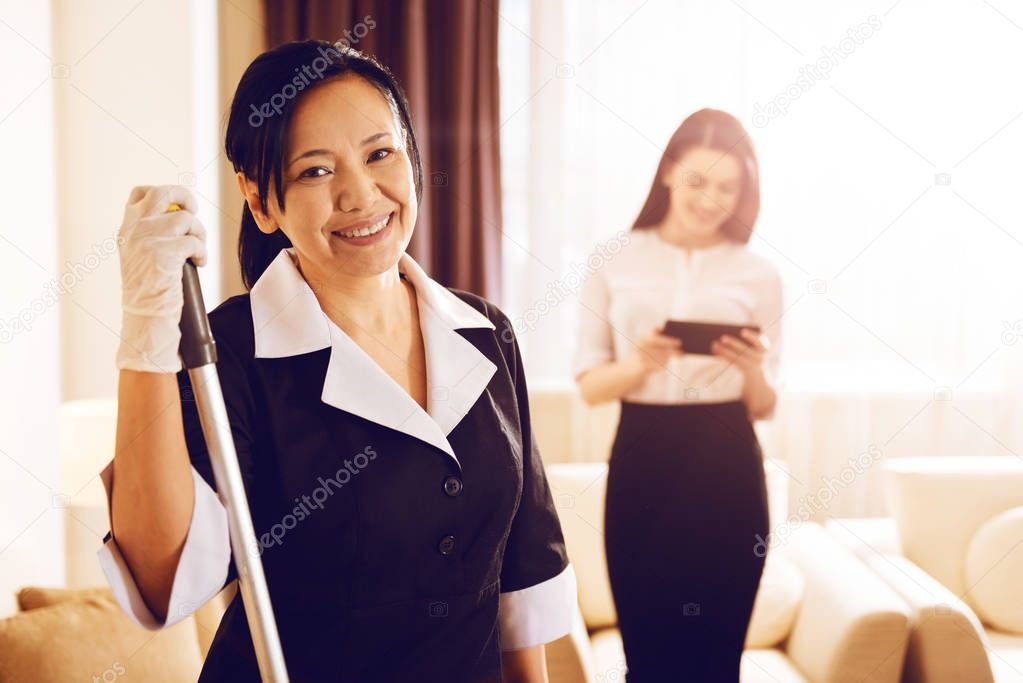 Positive delighted room cleaner posing on camera