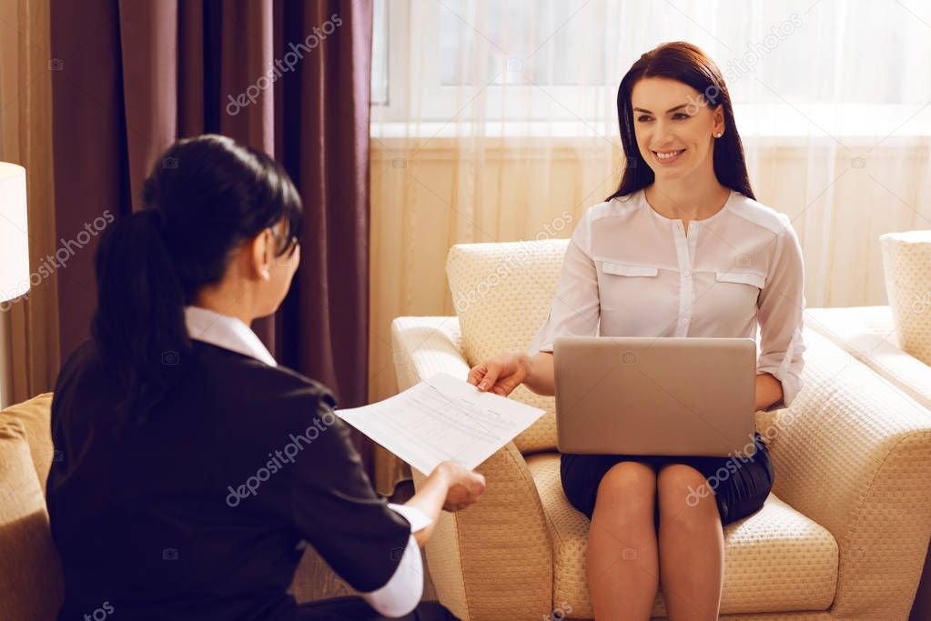 Cheerful female giving document to her helper