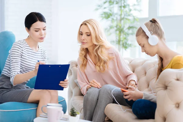 Seriózní blond žena při pohledu na poznámky k lékaři — Stock fotografie