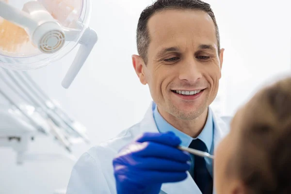 Позитивный стоматолог-мужчина, работающий с пациентом — стоковое фото