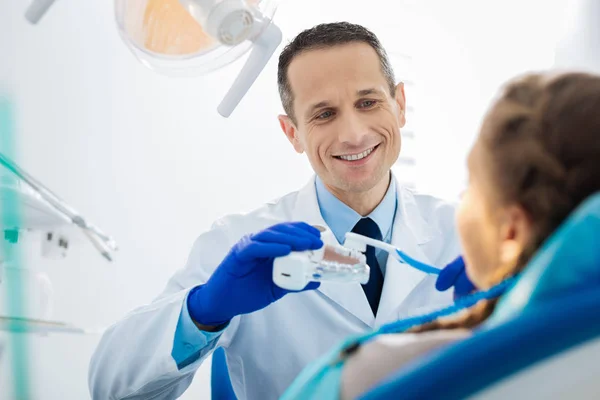 Радостный профессиональный стоматолог, показывающий технику чистки зубов — стоковое фото