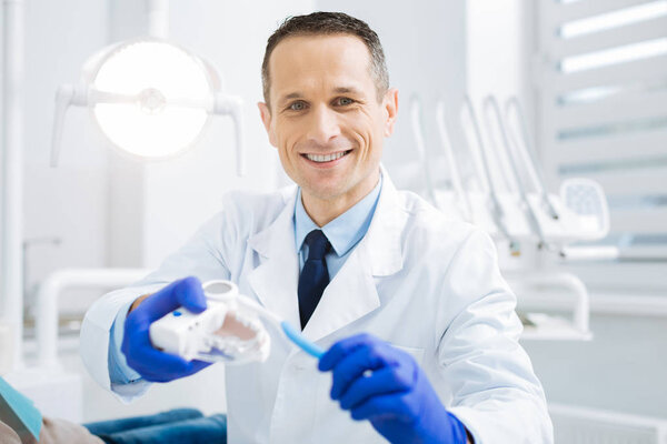 Joyful smart dentist looking at you