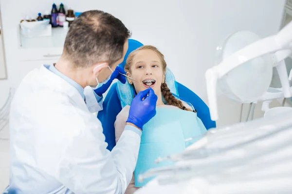 Delighted nice girl looking at her dentist — Stock Photo, Image