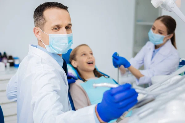 그의 동료와 함께 작업 하는 긍정적인 숙련 된 치과 의사 — 스톡 사진