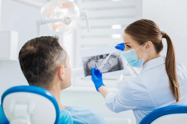 Bom dentista alegre apontando para a foto de raios X — Fotografia de Stock