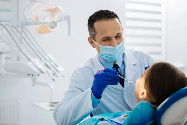 Dentista habilidoso inteligente usando um espelho — Fotografia de Stock