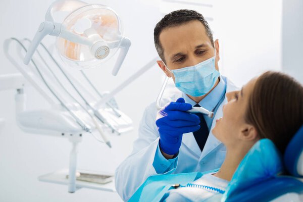 Professional experienced dentist treating his patients teeth