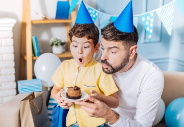 Neşeli baba ve oğul heyecanla doğum günü mumu üfleme
