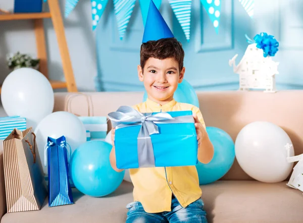 微笑的生日男孩摆在沙发上的礼品盒 — 图库照片