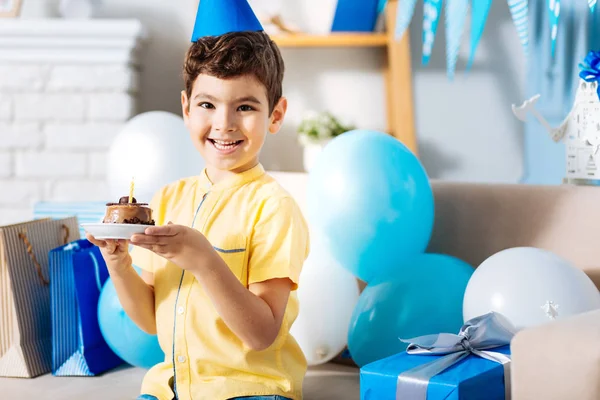 Lindo chico sentado en el sofá y la celebración de pastel de cumpleaños —  Fotos de Stock