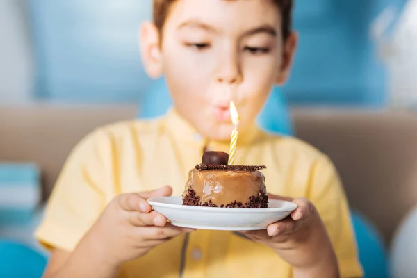 Agradable chico soplando vela en su pastel — Foto de Stock