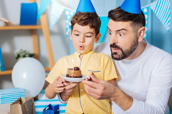 Upbeat padre e hijo soplando vela en pastel de cumpleaños —  Fotos de Stock