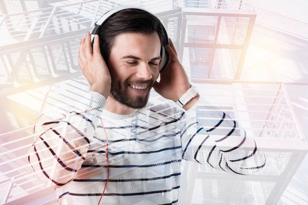 Glad ung man som njuter av musiken i moderna hörlurar — Stockfoto