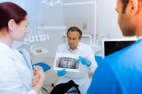 Dentista experiente e sério a apontar para a radiografia — Fotografia de Stock