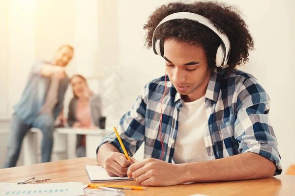 Koncentrerad student lyssnar på musik och att göra anteckningar — Stockfoto