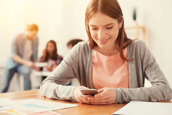 Glückliche Studentin blickt auf den Bildschirm des Smartphones — Stockfoto