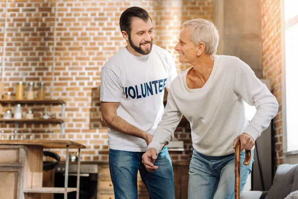 Behulpzame jonge vrijwilliger ondersteuning van een ouderdomsdeken — Stockfoto