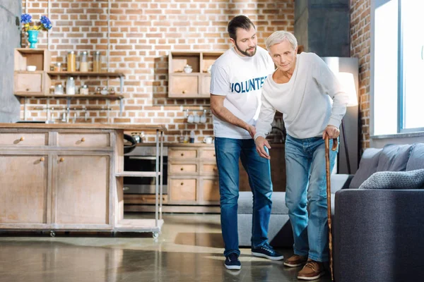 Calm attentive social worker supporting an old man — Stock Photo, Image