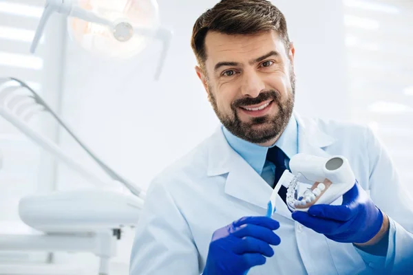 Nahaufnahme eines lächelnden Zahnarztes, der falsche Zähne in Händen hält — Stockfoto
