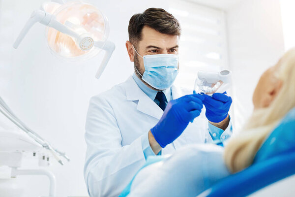 Close up of cheerful stomatologist with false teeth
