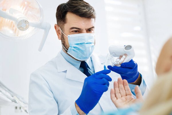 Close up of positive dentist holding false teeth in hands