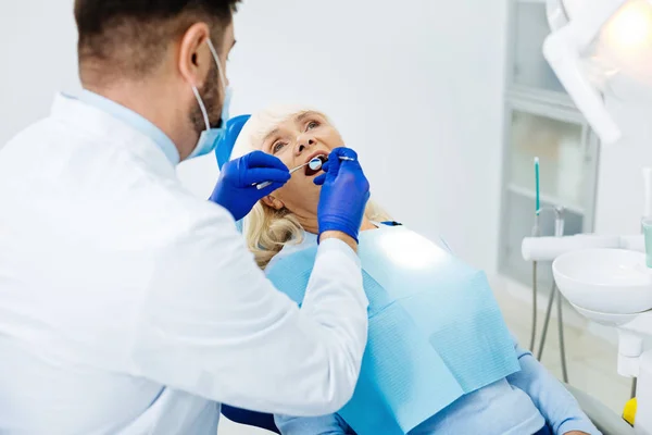 Dentista concentrado sosteniendo instrumento médico —  Fotos de Stock