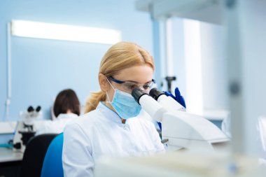 Ciddi genç araştırmacı laboratuarda mikroskop arıyor