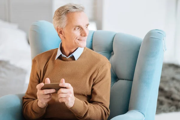 Positive minded gentleman in chair looking into vacancy and smiling — Stock Photo, Image