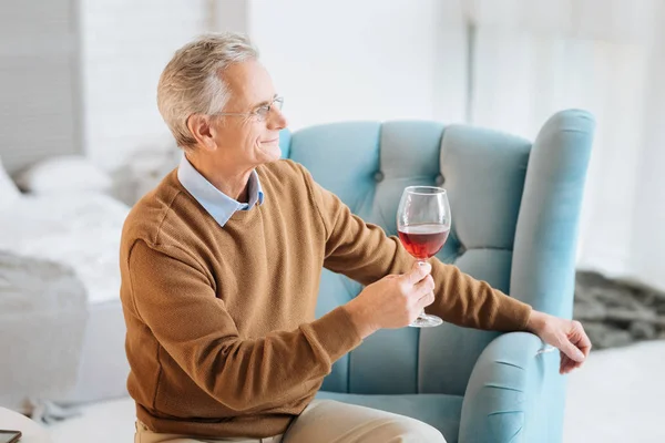 Cavalheiro idoso relaxado desfrutando de vinho tinto e sorrindo — Fotografia de Stock