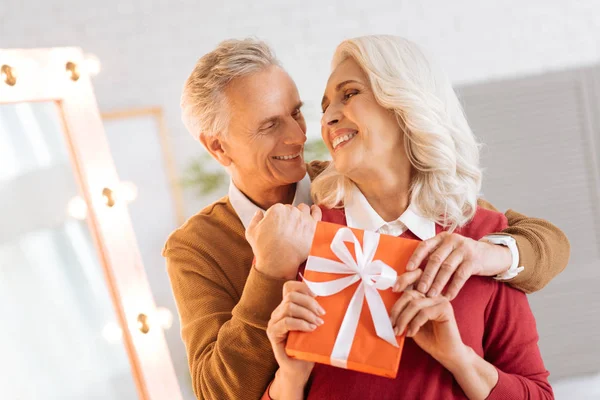 Bedårande senior par med gåva embracing tätt — Stockfoto