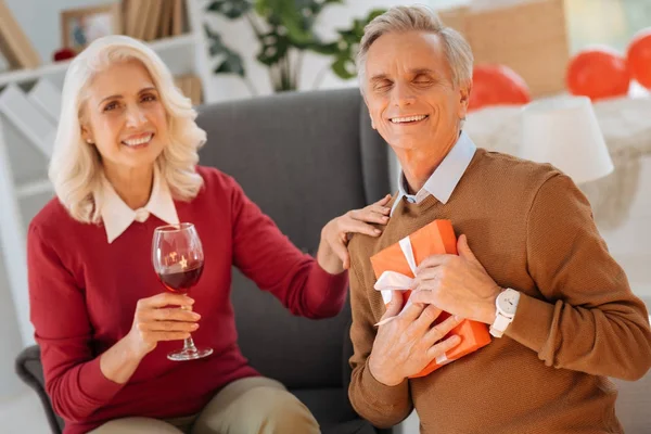 Любящий муж улыбается и обнимает подарок от своей жены — стоковое фото