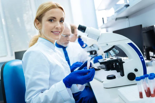 Uśmiechający się naukowiec siedzi w mikroskopie — Zdjęcie stockowe