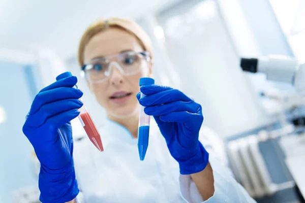 Vastbesloten wetenschapper holding reageerbuizen en het dragen van een uniform — Stockfoto