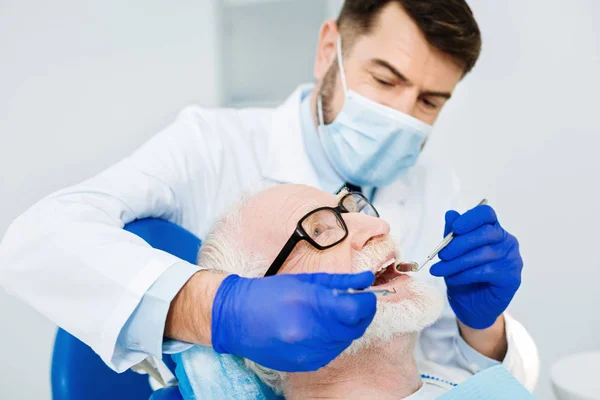 勤奋的牙医的关闭治疗他的病人 — 图库照片