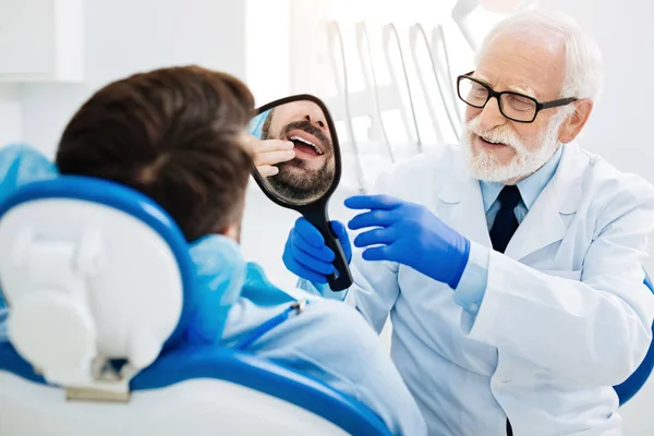 Zadowolony pacjent patrzy na zęby w lustrze — Zdjęcie stockowe