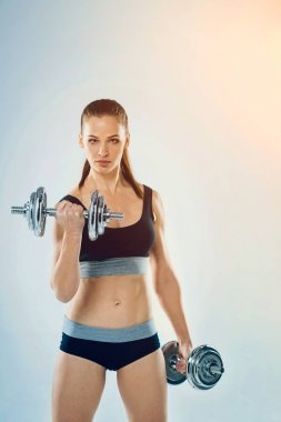 Kas sportif Bayan dumbbells ile arka plan üzerinde poz
