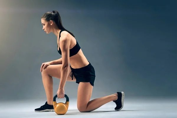 Jistý mladý sportovkyně cvičení s kettlebell — Stock fotografie