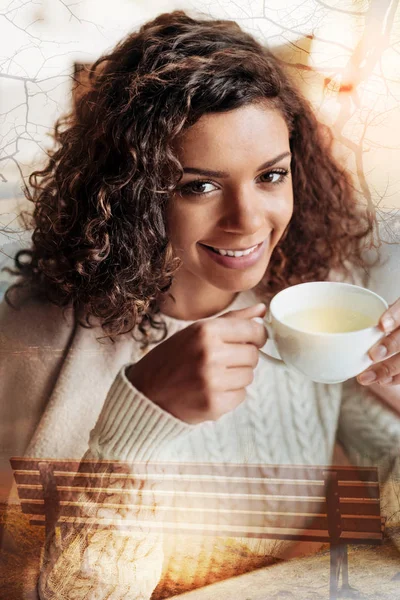 Hermosa joven sonriendo alegremente mientras bebe su té — Foto de Stock