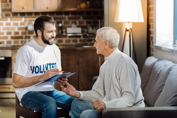 Milý ochotný dobrovolník zápis informací o důchodce — Stock fotografie