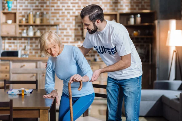 Freundliche, aufmerksame Freiwillige, die eine Seniorin unterstützt — Stockfoto