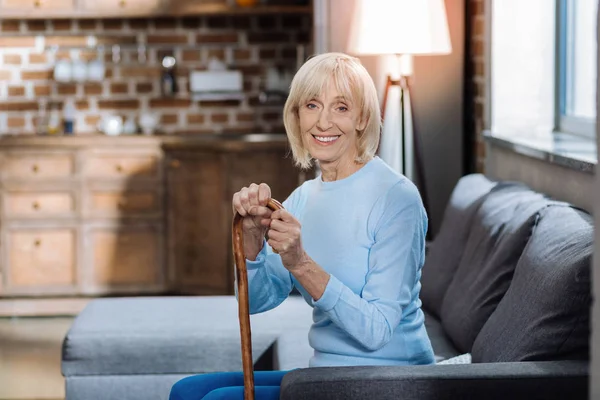 Glad pensionär sitter med en käpp och ler — Stockfoto