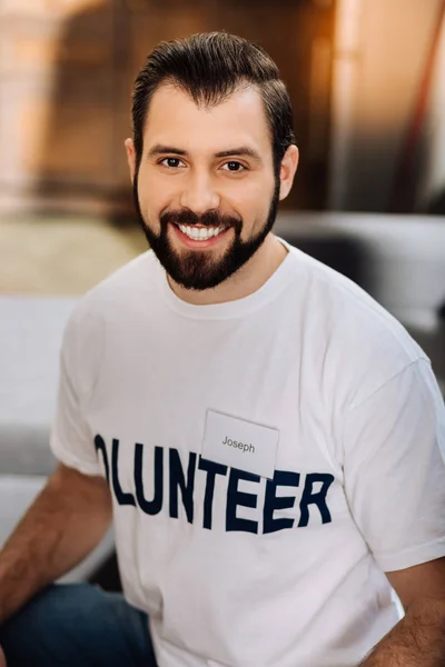 Cheerful young volunteer looking happy while being at work — Stock Photo, Image