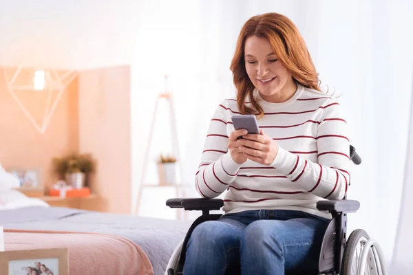 Alerta mujer sentada en una silla de ruedas con su teléfono — Foto de Stock