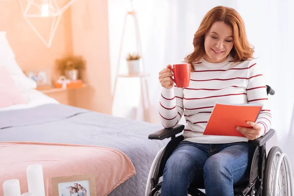 Disabled woman holding a cup and a notebook — Stock Photo, Image