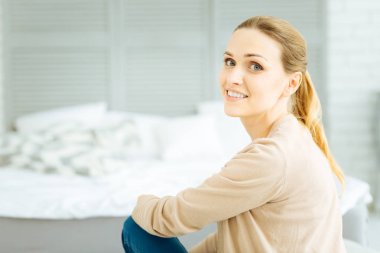 Rahat bir yatak üzerinde oturan neşeli sakin kadın