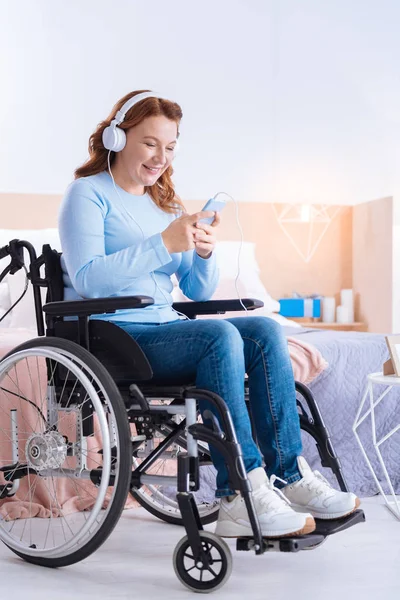 Mujer discapacitada que usa auriculares y su teléfono — Foto de Stock