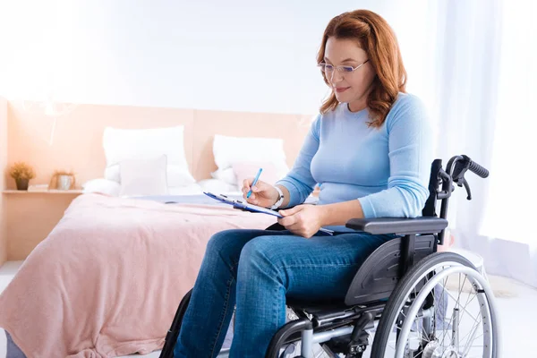 Femme handicapée écrivant sur une feuille de papier — Photo