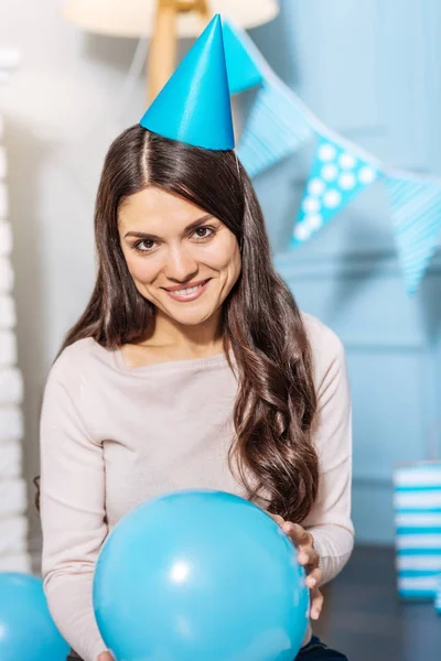 Mujer alegre en sombrero de fiesta sosteniendo un globo azul —  Fotos de Stock