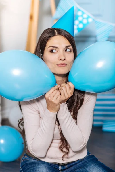 Glad kvinna som håller två ballonger nära hennes kinder — Stockfoto