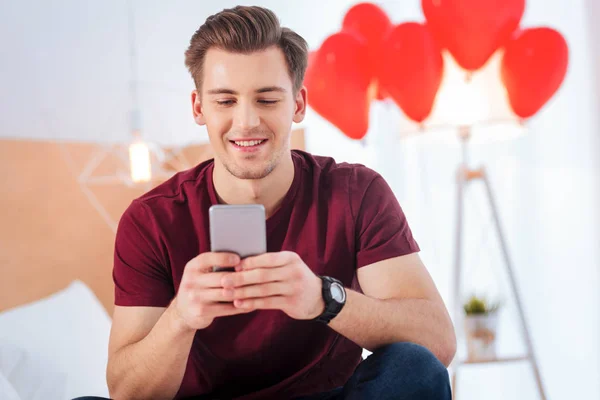 Joven alegre sonriendo mientras escribe el mensaje — Foto de Stock